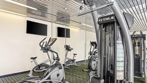 Uma academia com bicicletas ergométricas, esteiras e uma máquina de pesos.