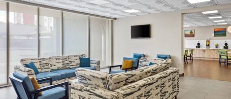 Un área de estar moderna con sofás y sillones estampados, un televisor de pantalla plana y obras de arte en las paredes.