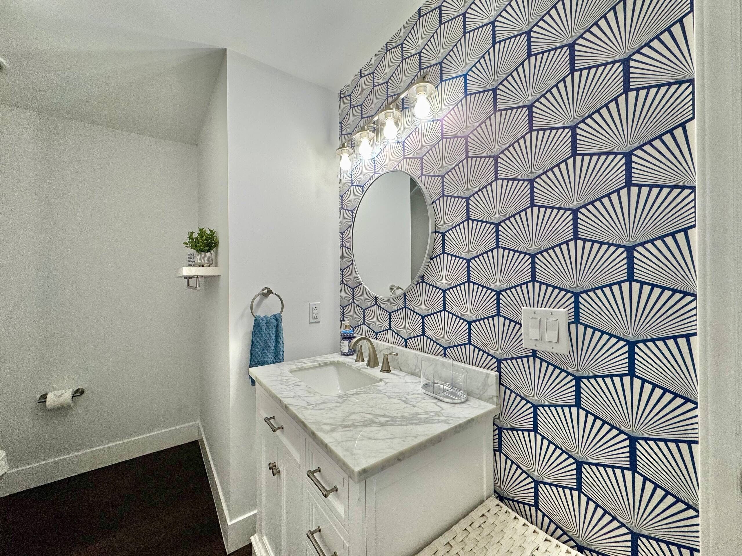 A bathroom with a white vanity, a mirror, and a patterned wall.