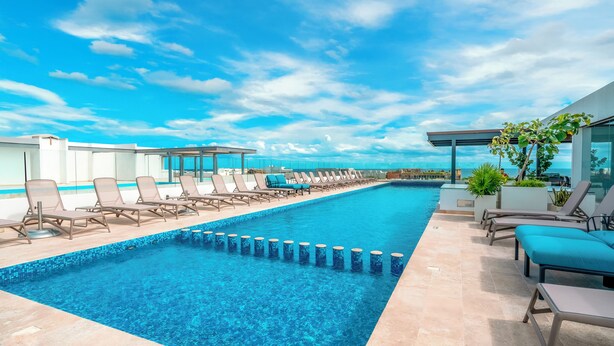 A rooftop infinity pool with lounge chairs and a clear view of the city skyline. - 2 BR Condo - Rooftop Pool At Ipanema 504 (Playa del Carmen)