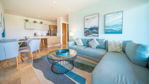 A modern living room with a sofa, a coffee table, and a dining area with chairs and a table. - 2 BR Condo - Rooftop Pool At Ipanema 504 (Playa del Carmen)