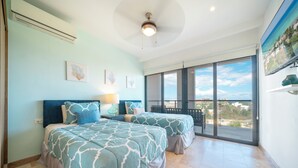 A bedroom with two beds, a ceiling fan, and a large sliding glass door leading to a balcony. - 2 BR Condo - Rooftop Pool At Ipanema 504 (Playa del Carmen)