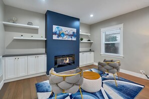 Un salon moderne avec une cheminée, des meubles blancs et des meubles bleus et gris.