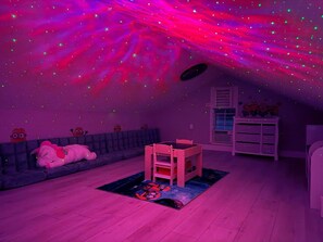 Ein Zimmer in Lila, mit einer Couch, einem Tisch und einem Minion-Plüschtier.