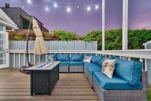 Une terrasse extérieure avec un canapé bleu, une table et des guirlandes lumineuses.
