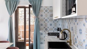 Une cuisine équipée d’une cuisinière à gaz, d’un évier et d’une fenêtre avec des rideaux.