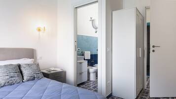 Ein Hotelzimmer mit Bett, Nachttisch, offenem Badezimmer und Kleiderschrank.