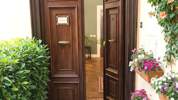 Une porte à deux battants en bois, avec un paillasson, des plantes en pot et des jardinières de chaque côté.