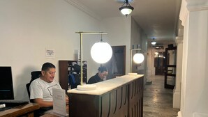 A reception desk with a wooden counter and two people seated behind it. - Bugambilias Hotel Hacienda (Durango)