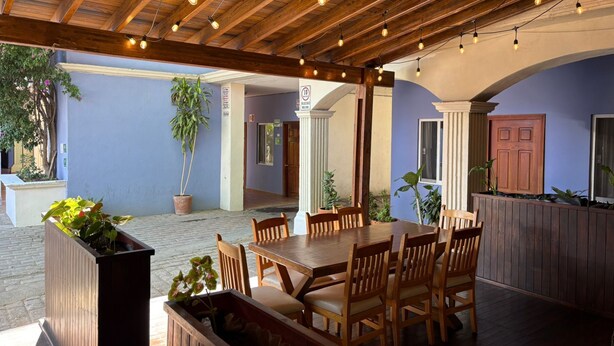 An outdoor patio with a wooden table and chairs, surrounded by potted plants and a wooden fence. - Bugambilias Hotel Hacienda (Durango)