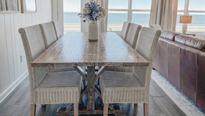 Un coin repas avec une table en bois, des chaises en osier et un canapé en osier.