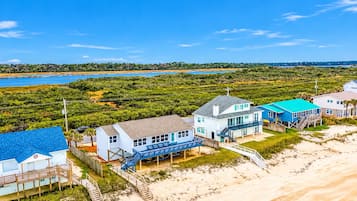 A coastal property with multiple buildings, including a house with a blue roof and a larger structure with a blue exterior.