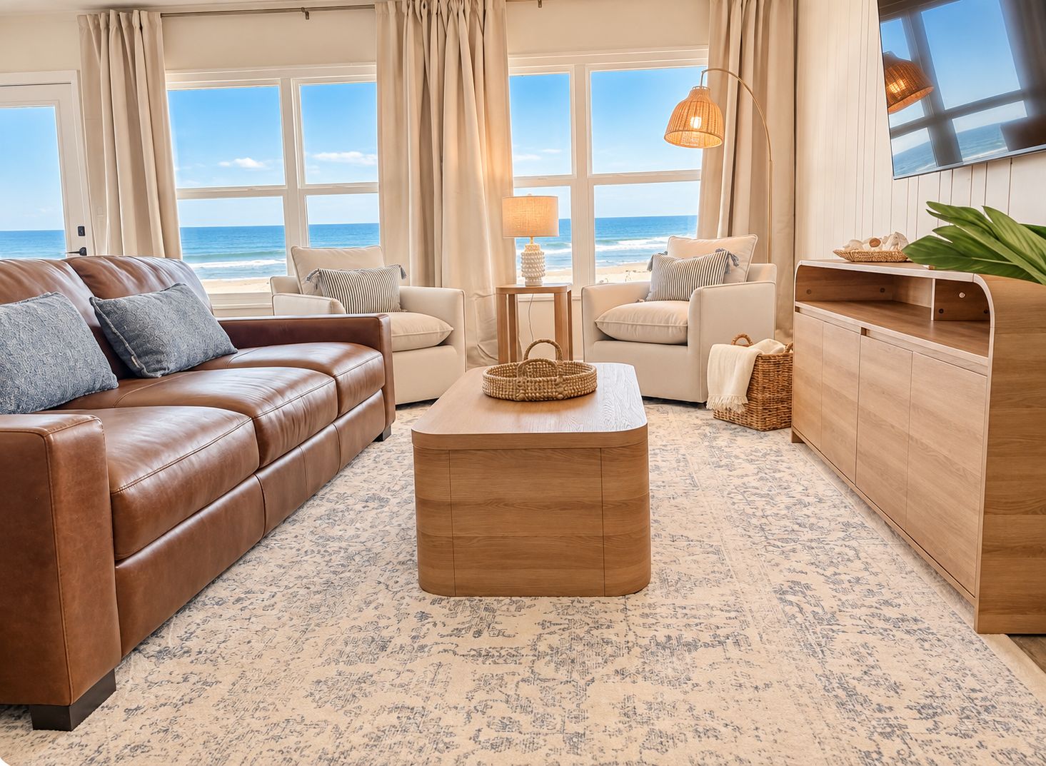 A living room with a brown leather sofa, a wooden coffee table, and a view of the ocean through large windows.