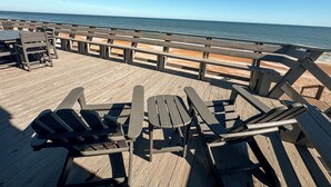 Une terrasse en bois avec des tables et des chaises pour pique-niquer, donnant sur une plage.