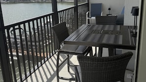 Un balcon avec une table et des chaises, une vue sur une étendue d’eau et un élément décoratif mural.