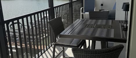 Uma varanda com mesa e cadeiras, vista para a água e um objeto decorativo na parede.