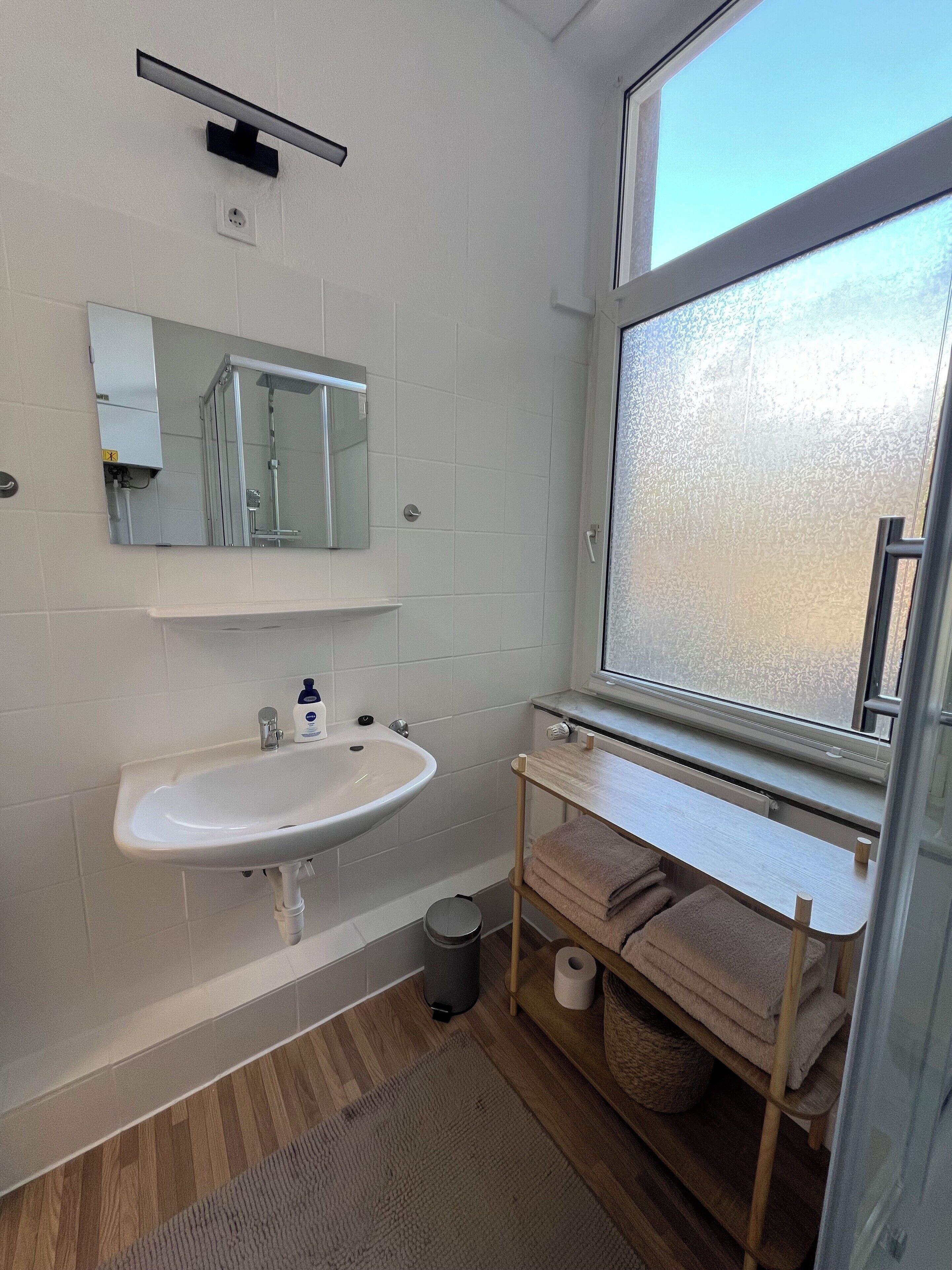 Un bany modern amb un lavabo, un mirall i una finestra blancs.