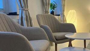 Una sala de estar moderna con tres sillones color beige y una pequeña mesa redonda.