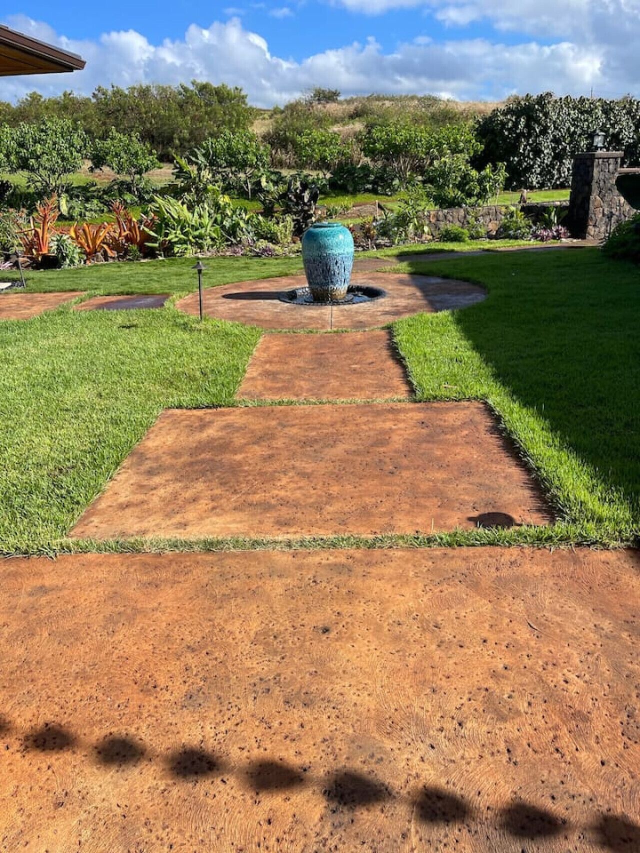 Un chemin de jardin qui mène à un grand bac à fleurs bleu.