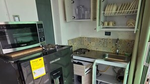 A compact kitchen with a refrigerator, microwave, and gas stove. - Loft Mr1-4g Facing the sea in a High Level Neighborhood (Cartagena)