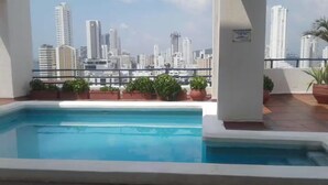 A rooftop pool with a city skyline view, potted plants, and a safety sign. - Loft Mr1-4g Facing the sea in a High Level Neighborhood (Cartagena)