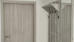 A room with a wooden door and a coat rack with hooks. - Vacation apartment Hof Lanze with a view of the Eichenallee (Prezelle)