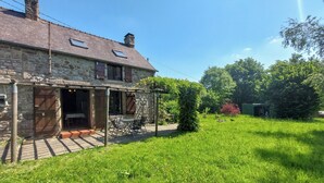 Une maison en pierre avec un patio couvert et une cour gazonnée.