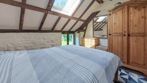 Une chambre à coucher avec un lit, une armoire en bois et un puits de lumière.