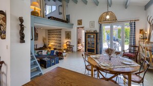 A cozy, well-lit dining area with a wooden table set for four, surrounded by vintage chairs. A staircase leads to an upper level with a loft bed and a hanging light fixture. - 3 bedroom awesome home in Saint-Denis-d'Oléron (Saint-Denis-d'Oléron)