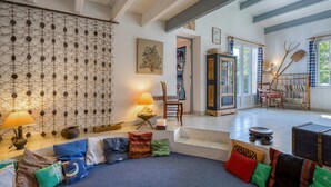 A cozy living room with a patterned wall, a sofa with colorful cushions, a lamp, and a bookshelf. - 3 bedroom awesome home in Saint-Denis-d'Oléron (Saint-Denis-d'Oléron)