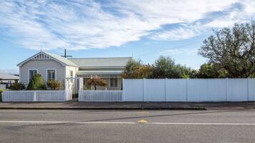 A single-story house with a gabled roof, a fenced yard, and a clear sky.