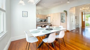 A dining area with a white table, four chairs, and a chandelier.