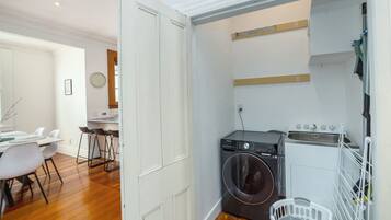 A compact kitchen with a washing machine, a sink, and a drying rack.