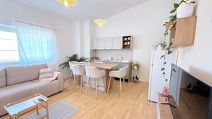 A modern kitchen with a central island, a dining area with chairs, a sofa, a coffee table, and a fireplace. - Luna Serene Garden House | Jacuzzi (Zadar)