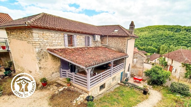 A stone house with a tiled roof, a balcony, and a small garden area. - Gîtes de France® - Bri-Gîte (SAINT MEDARD)