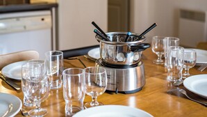 A dining table set with multiple wine glasses, a stainless steel electric kettle, and a white plate.