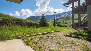 A pathway leading to a wooden structure with a view of mountains and a clear sky.