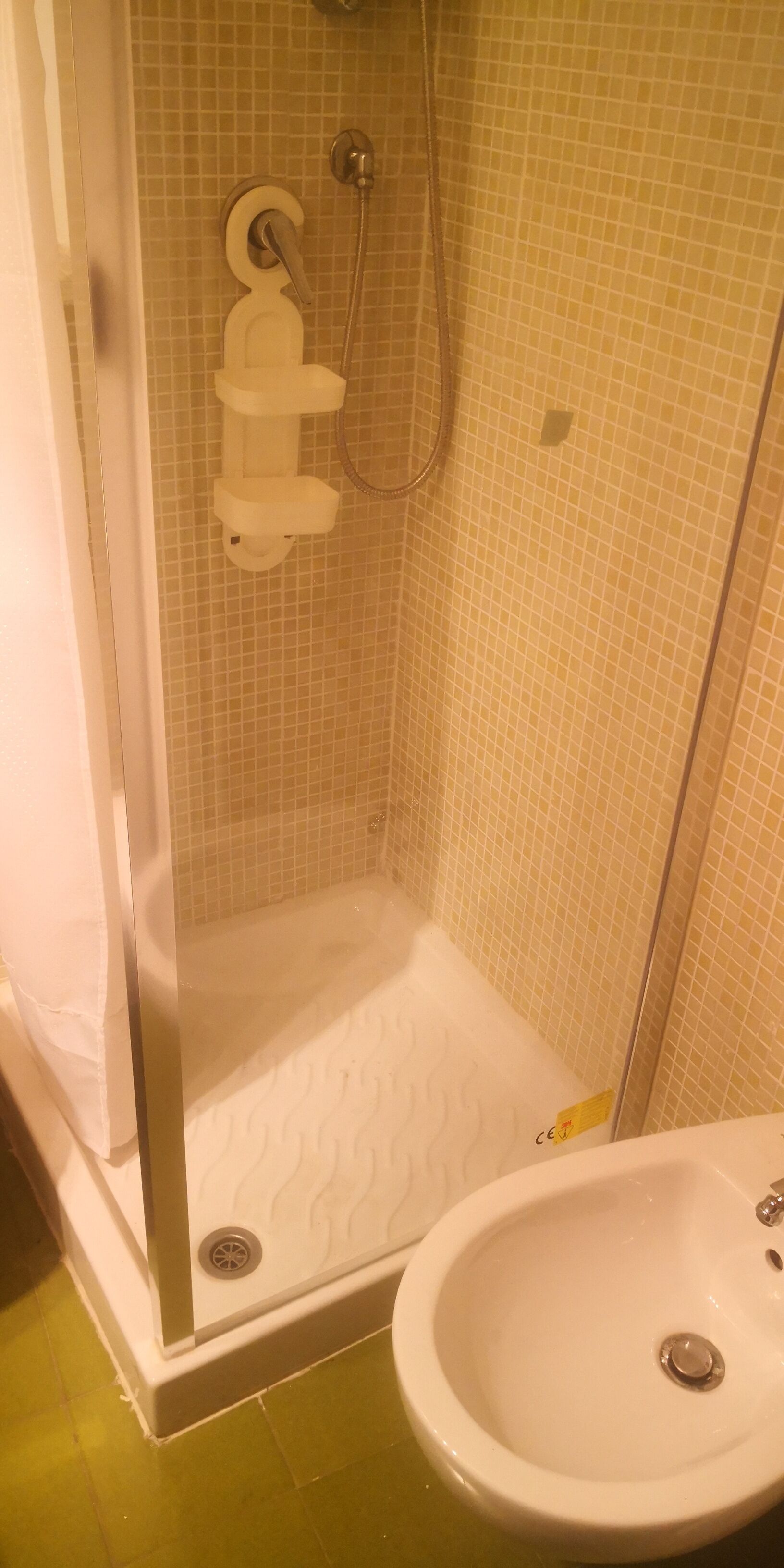 Une salle de bain avec une douche, un lavabo et des murs carrelés.