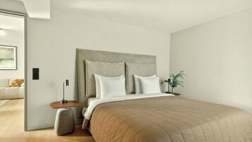 A bedroom with a bed, bedside table, lamp, and a plant.