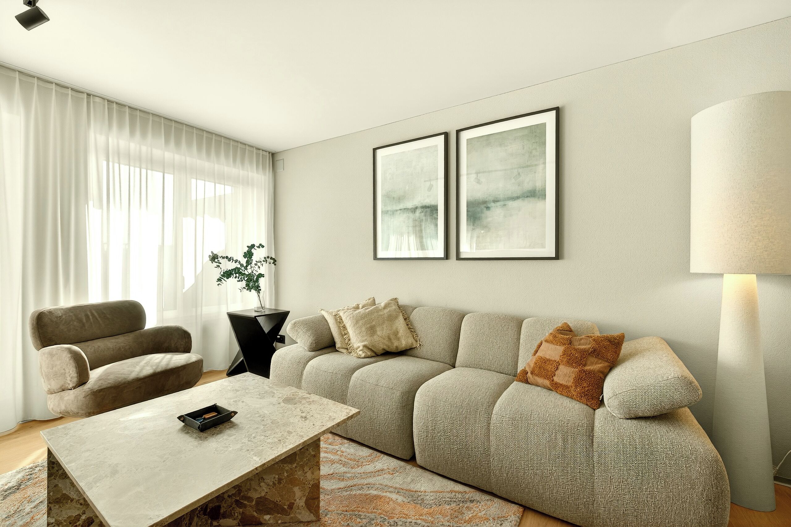 Ein Wohnzimmer mit einer Couch, einem Couchtisch, einer Lampe und zwei gerahmten Bildern an der Wand.