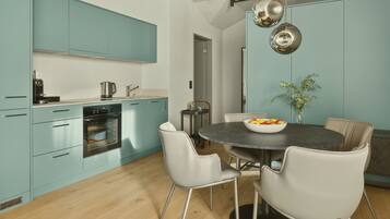 A modern kitchen with teal cabinets, a round dining table, and white chairs.