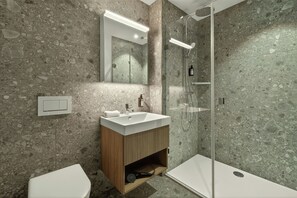 A modern bathroom with a freestanding shower, a sink with a wooden vanity, and a toilet. - Belmont Residences (Opfikon)
