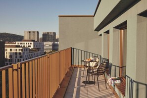A balcony with a table and chairs, a wooden fence, and a view of buildings in the background. - Belmont Residences (Opfikon)