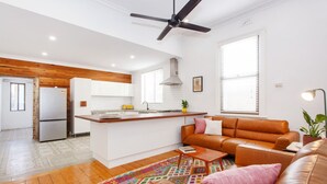 Una cocina moderna con armarios blancos, una isla de madera y un ventilador de techo.