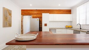 Una cocina moderna con encimera de madera, armarios blancos y pared de ladrillo.