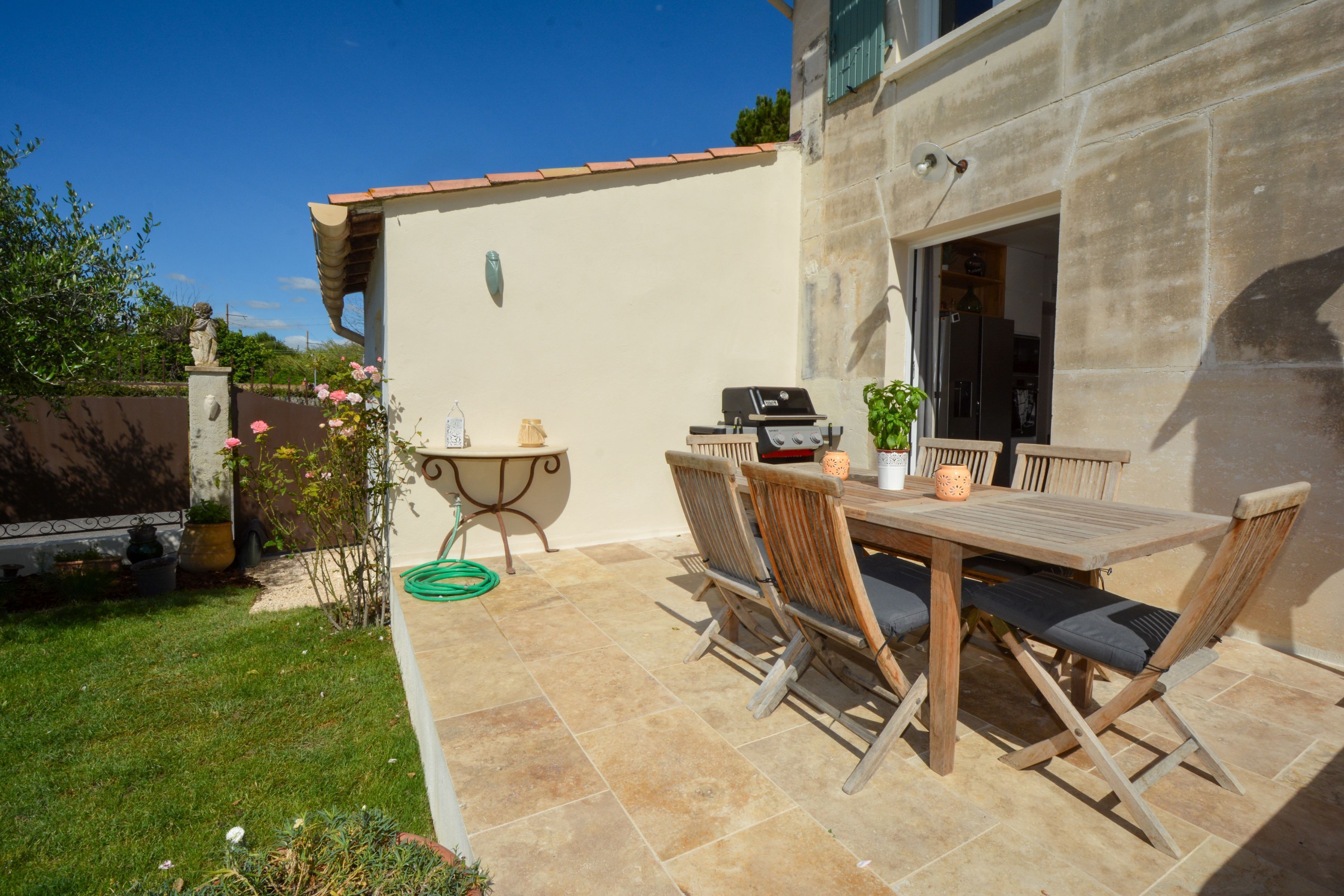 A patio with a table and chairs, a grill, and a statue.