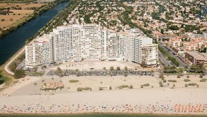 Un hotel costero con varios edificios altos, una playa y un estacionamiento.