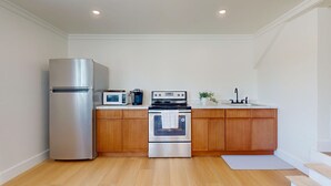 Una cocina compacta equipada con refrigerador, microondas, estufa y lavabo.