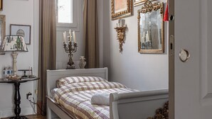 Une chambre à coucher avec un lit, un ventilateur de plafond, une fenêtre avec des rideaux et des lampes fixées au mur.
