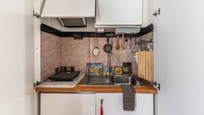 Une cuisine de taille réduite, dotée d’un évier, d’un plan de travail en bois et d’un pare-feu en carrelage.